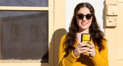 woman-wearing-yellow-sweater-looking-at-phone-smiling
