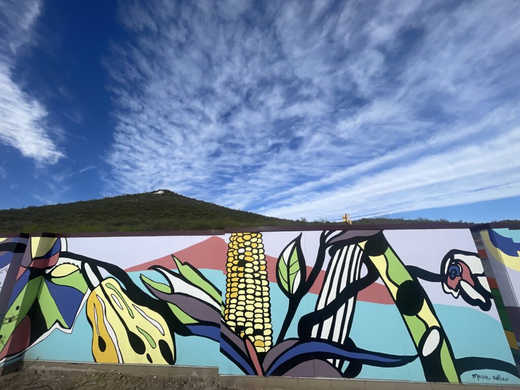 A mural of plants sits below a mountain with a white "A" painted at the top of the mountain.