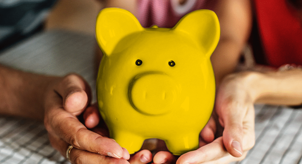two hands holding yellow piggy bank