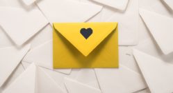 yellow-envelope-with-heart-on-top-of-pile-of-plan-white-envelopes